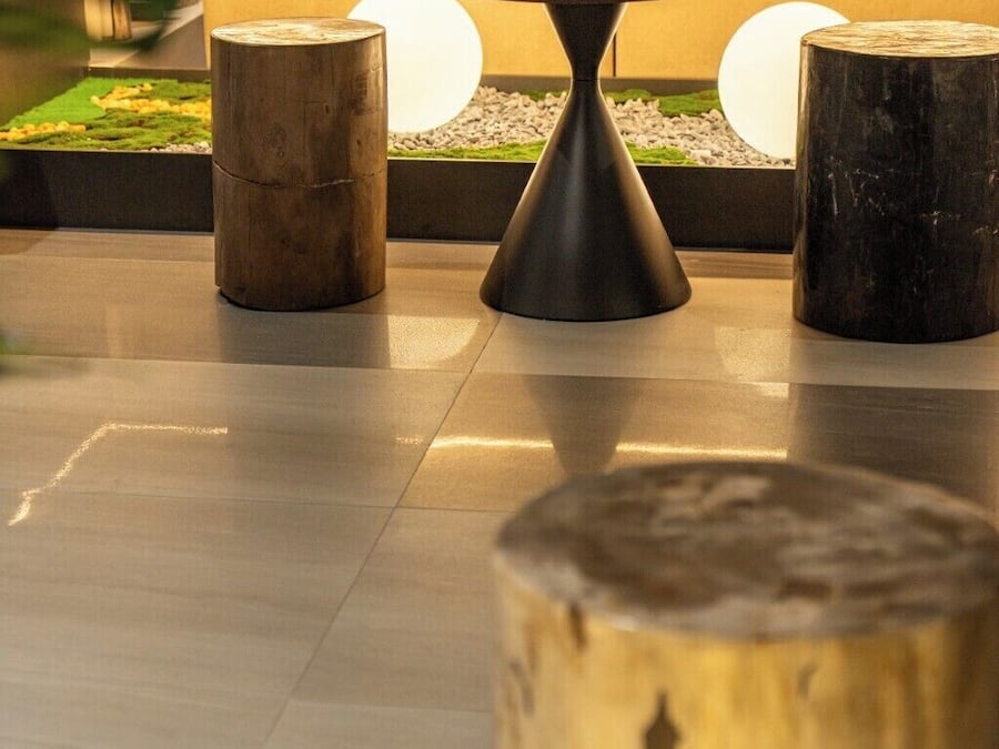 Un espacio al aire libre moderno con una mesa redonda y tres taburetes de madera.