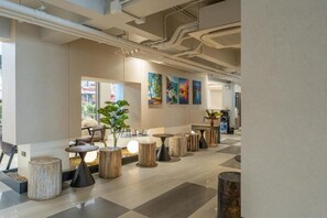 A modern interior with a checkered floor, wooden tables, and abstract paintings on the wall. - Wachi Hotel (Songkhla)