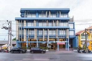 A modern hotel with a blue facade, large windows, and a sign indicating it is a WACHIHOTEL. - Wachi Hotel (Songkhla)