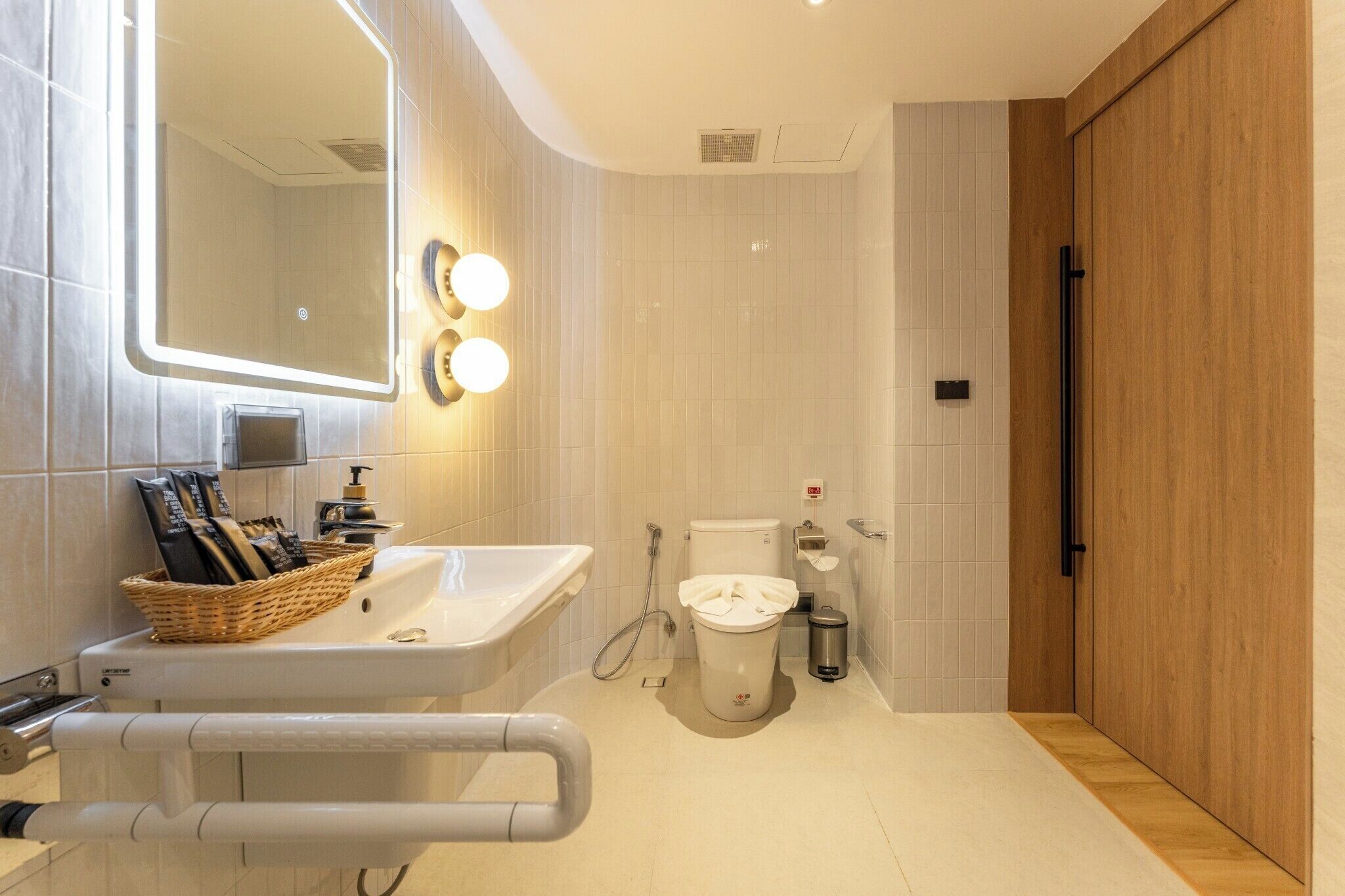 A modern bathroom with a large mirror, a sink, a toilet, and a shower area.