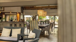 Un interior moderno con mobiliario de mimbre, una zona de bar y ventanas amplias que ofrecen vistas.