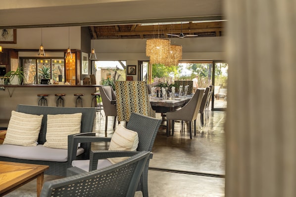 Un interior moderno con mobiliario de mimbre, una zona de bar y ventanas amplias que ofrecen vistas.