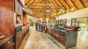 Uma cozinha espaçosa com armários de madeira, uma ilha grande e um teto alto com vigas aparentes.