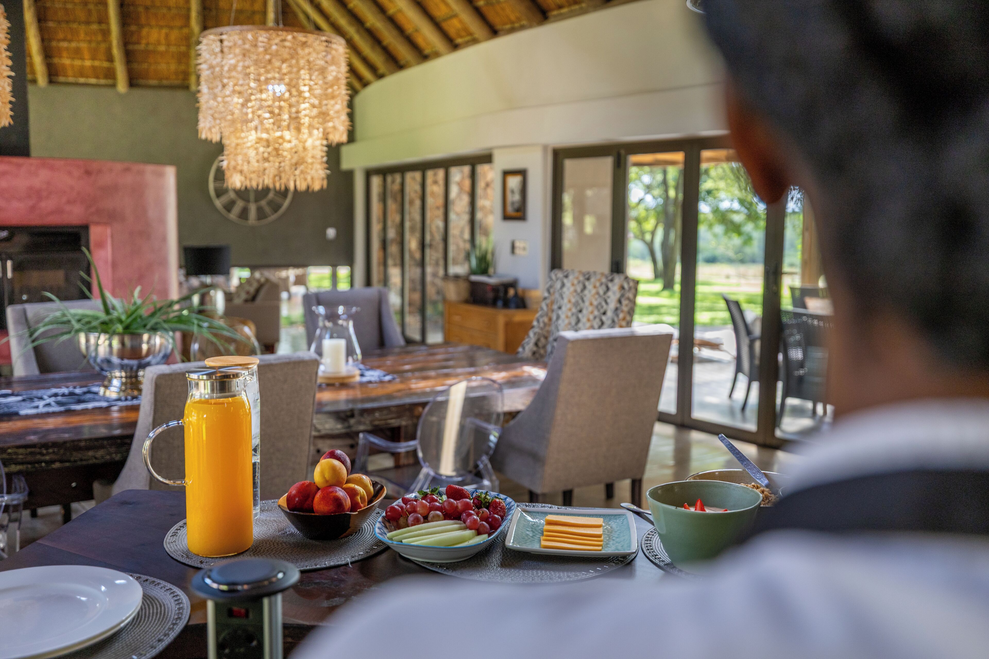 A dining area with a table set for breakfast, including fruit and a pitcher of orange juice.