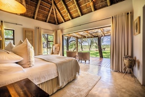 Um quarto com uma cama grande, teto de madeira e vista para o exterior.