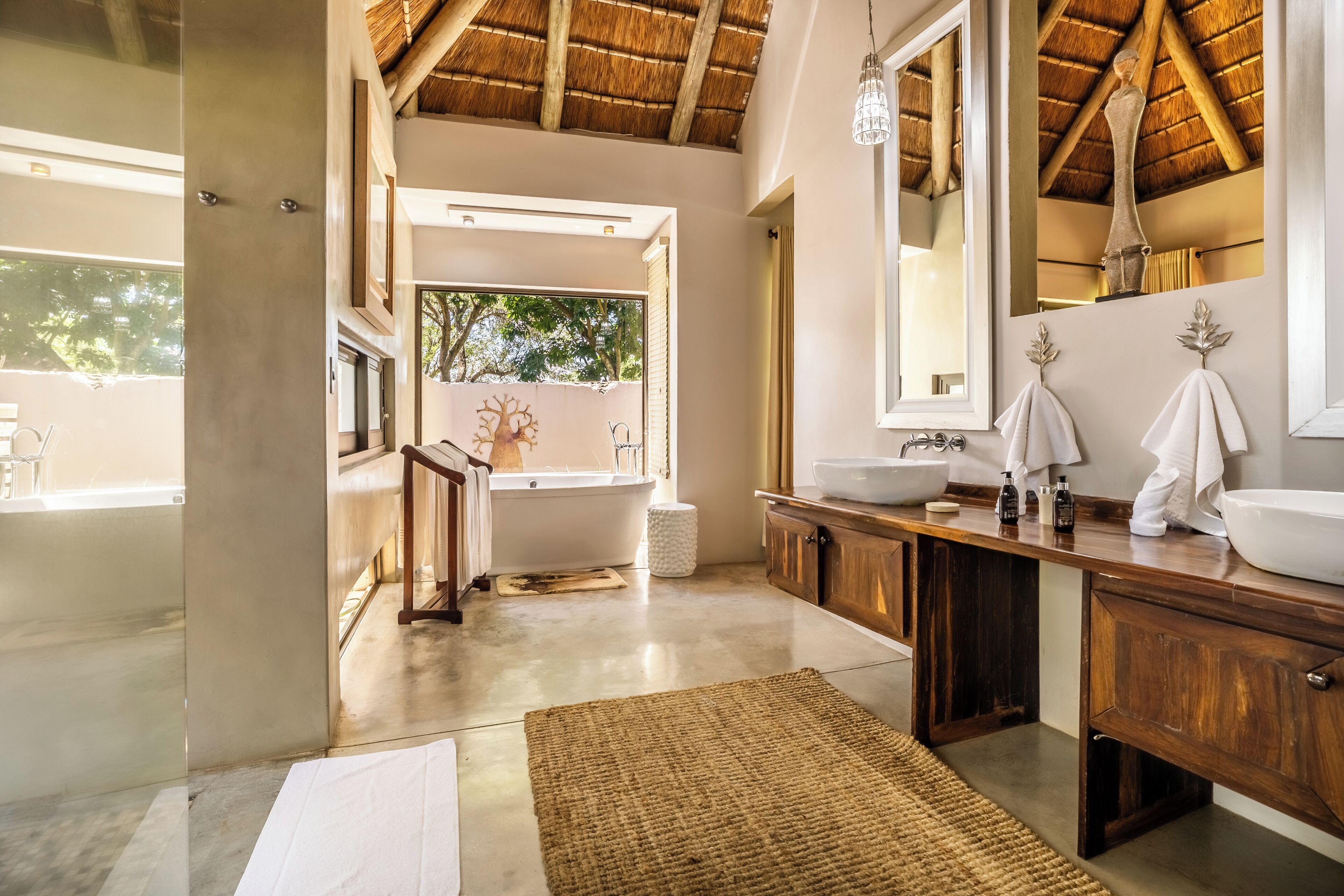 A modern bathroom with a bathtub, a large mirror, wooden cabinets, and a concrete floor.