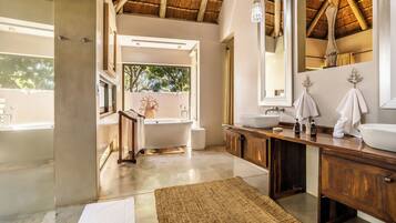 A modern bathroom with a bathtub, a large mirror, wooden cabinets, and a concrete floor.