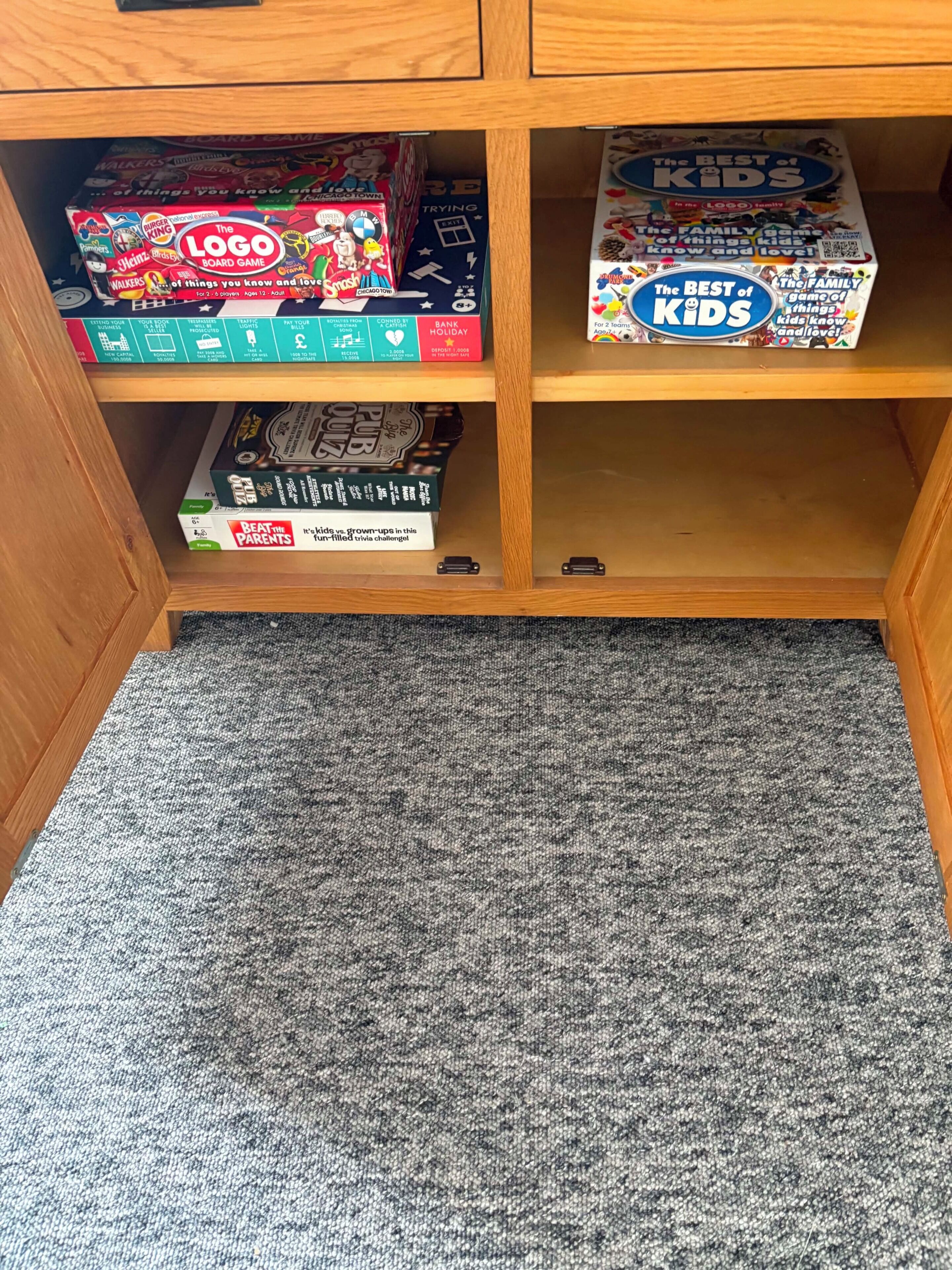 A wooden shelf with board games, including 'The Logo Board Game' and 'The Best of Kids.'