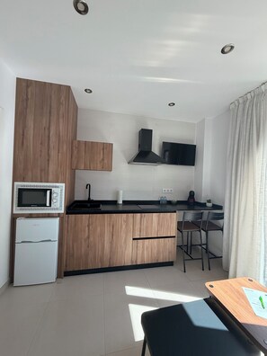 Una cocina moderna con microondas, estufa y armarios de madera.