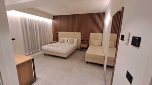 Een moderne hotelkamer met een groot bed, een kleinere zithoek, een bureau en een spiegel.