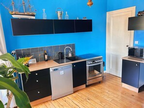 Une cuisine compacte équipée d’un lave-vaisselle, d’une cuisinière et d’un petit évier.