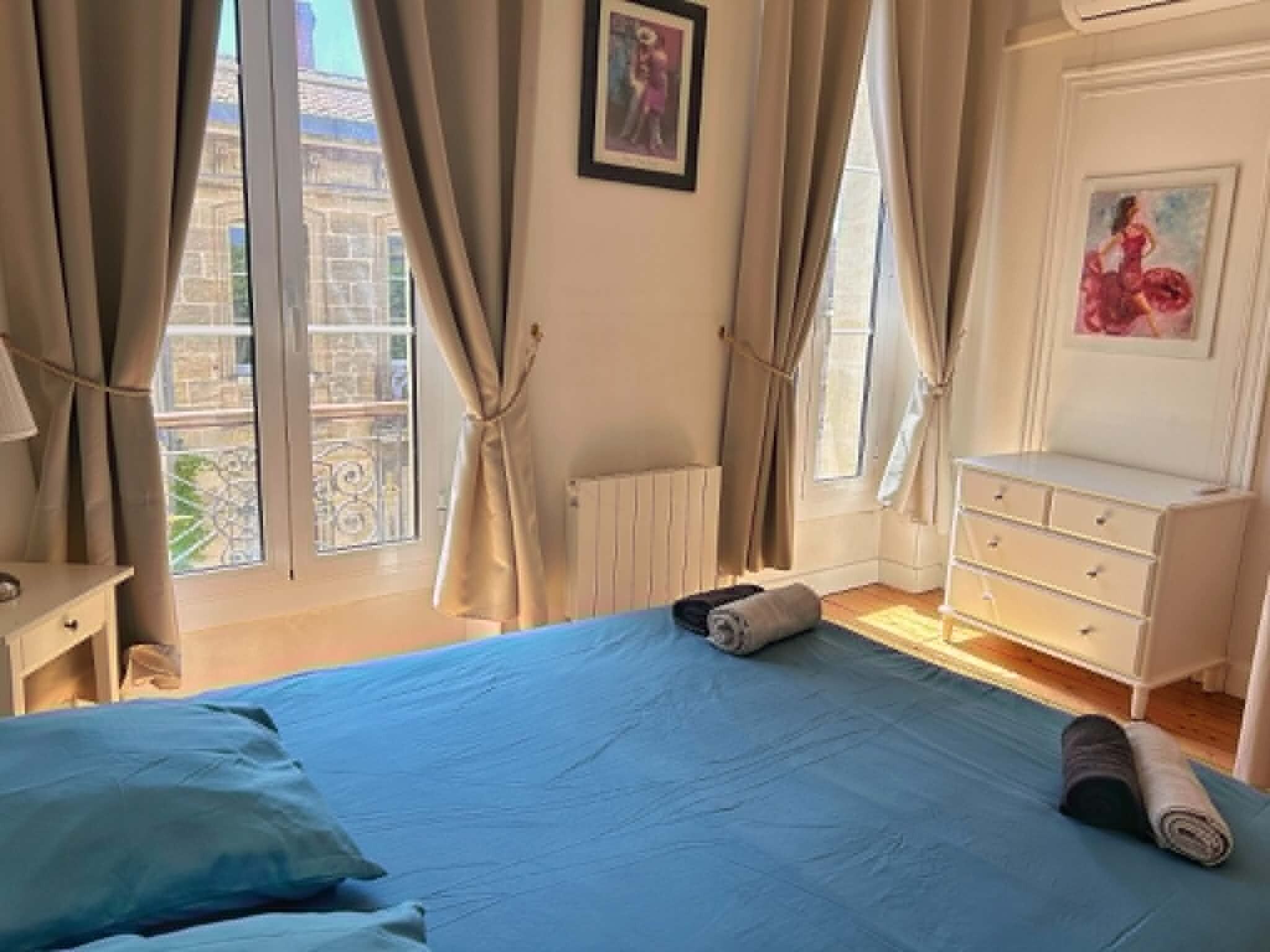 Ein Schlafzimmer mit einem Bett, einer Kommode und einem Fenster mit Vorhängen.