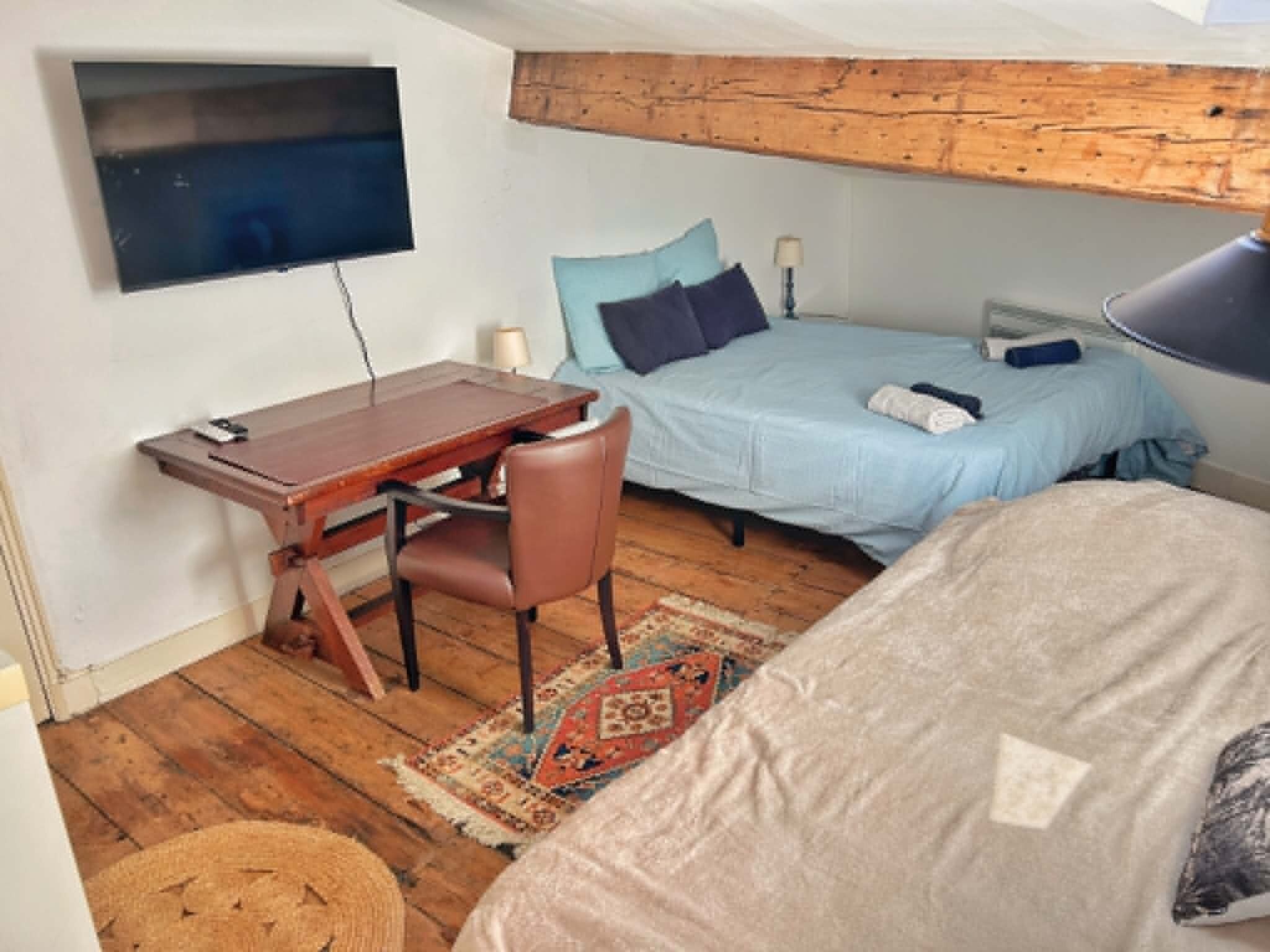 A bedroom with a bed, a desk, and a chair.