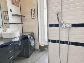 A modern bathroom with a sink, mirror, black cabinet, washing machine, and a shower enclosure. - Charming T3 60 m² | Bright duplex with high ceilings | Centre Bordeaux (Bordeaux)
