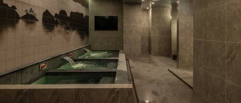 A spa area with three hot tubs, tiled walls, and a digital clock.