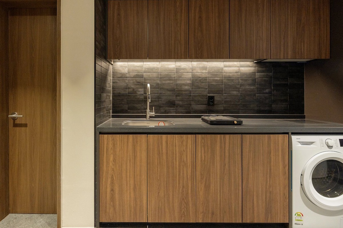 Cocina compacta con lavadora integrada, un lavabo y armarios de madera.