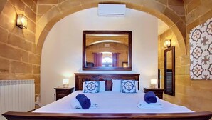 Camera d'albergo con un letto grande, uno specchio sopra il letto, pareti in pietra e un termosifone.