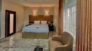 Habitación de hotel con cama, mesitas de noche, una silla y vistas al exterior.