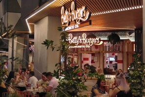 Ein Restaurant namens 'Betty's Burgers' mit leuchtendem Neonzeichen, Außenbereich und Einblick in den Innenraum inklusive Theke und Personal.