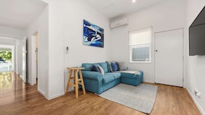 Una sala de estar moderna con un sofá seccional azul, un taburete de madera, un cuadro y un ventanal grande.