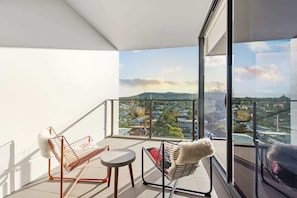 A balcony with two chairs, a small table, and a view of a cityscape. - Captivating Convenience! 1bed/1bath/1car/views (Brisbane)