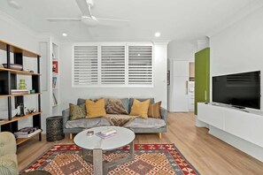 A modern living room with a sofa, coffee table, and TV. - The Sanctuary! 1bed, 1bath, 1car, Pool~teneriffe (Brisbane)