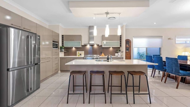 A modern kitchen with a central island, stainless steel appliances, and bar stools.