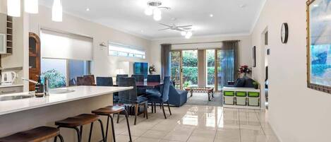 A modern kitchen with a bar area, dining chairs, and a view of the outdoors.