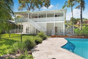 A two-story house with a pool, a staircase, and a fenced yard.