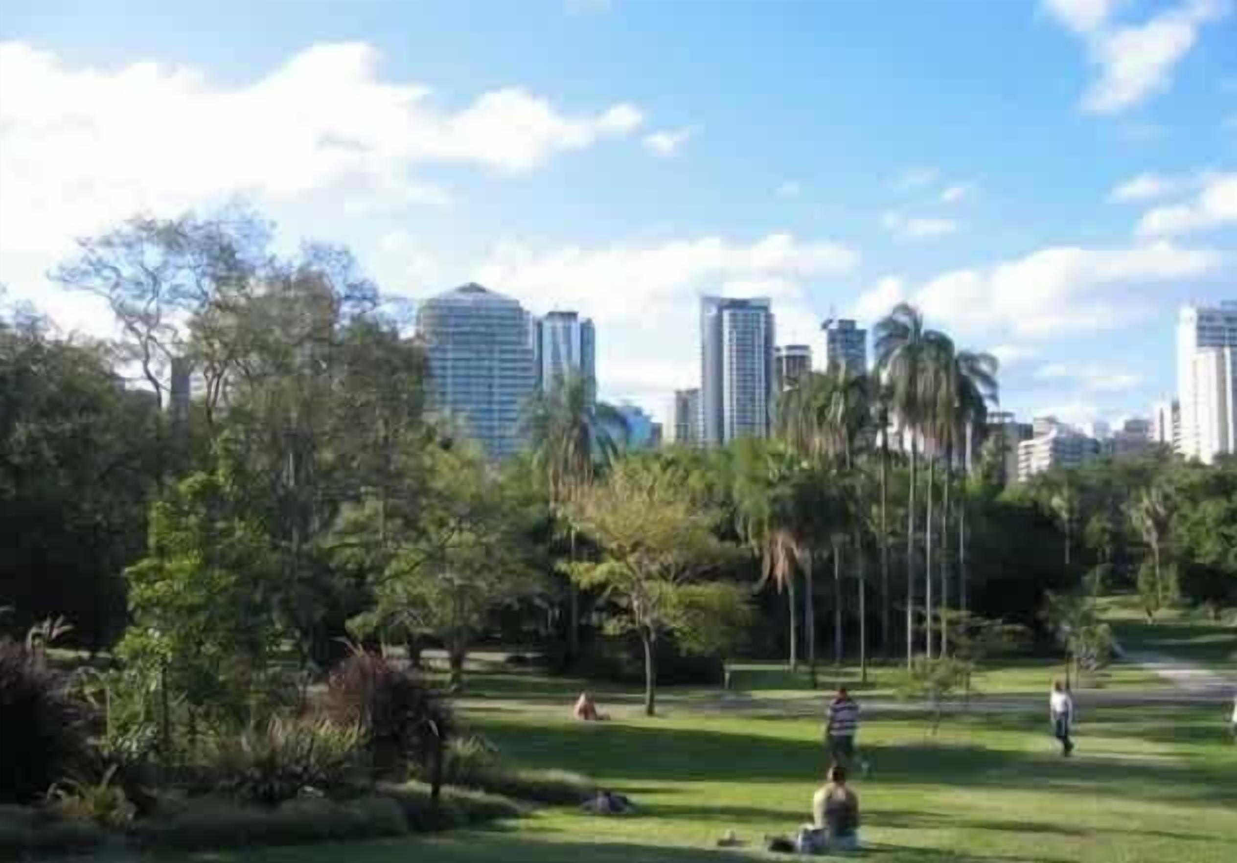 A park with grass, trees, and a city skyline in the background.