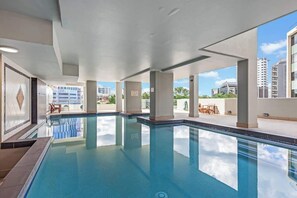 Una piscina con agua cristalina, rodeada de columnas y vistas a edificios.