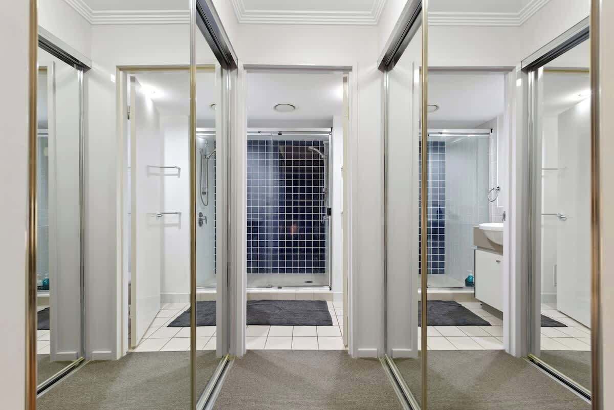 A modern bathroom with a glass shower enclosure, a white sink, and a tiled shower area.