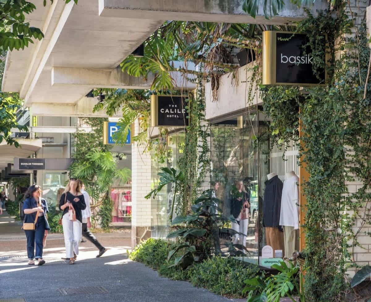 A hotel entrance with a sign for 'The Calile Hotel' and a storefront with a sign for 'bassik.'