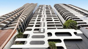 A high-rise building with a modern architectural design, featuring multiple balconies and large windows.