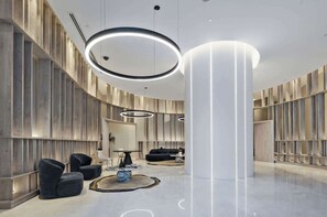 Eine moderne Lobby mit gewölbter Decke, runden Leuchten und einer zentralen Säule.