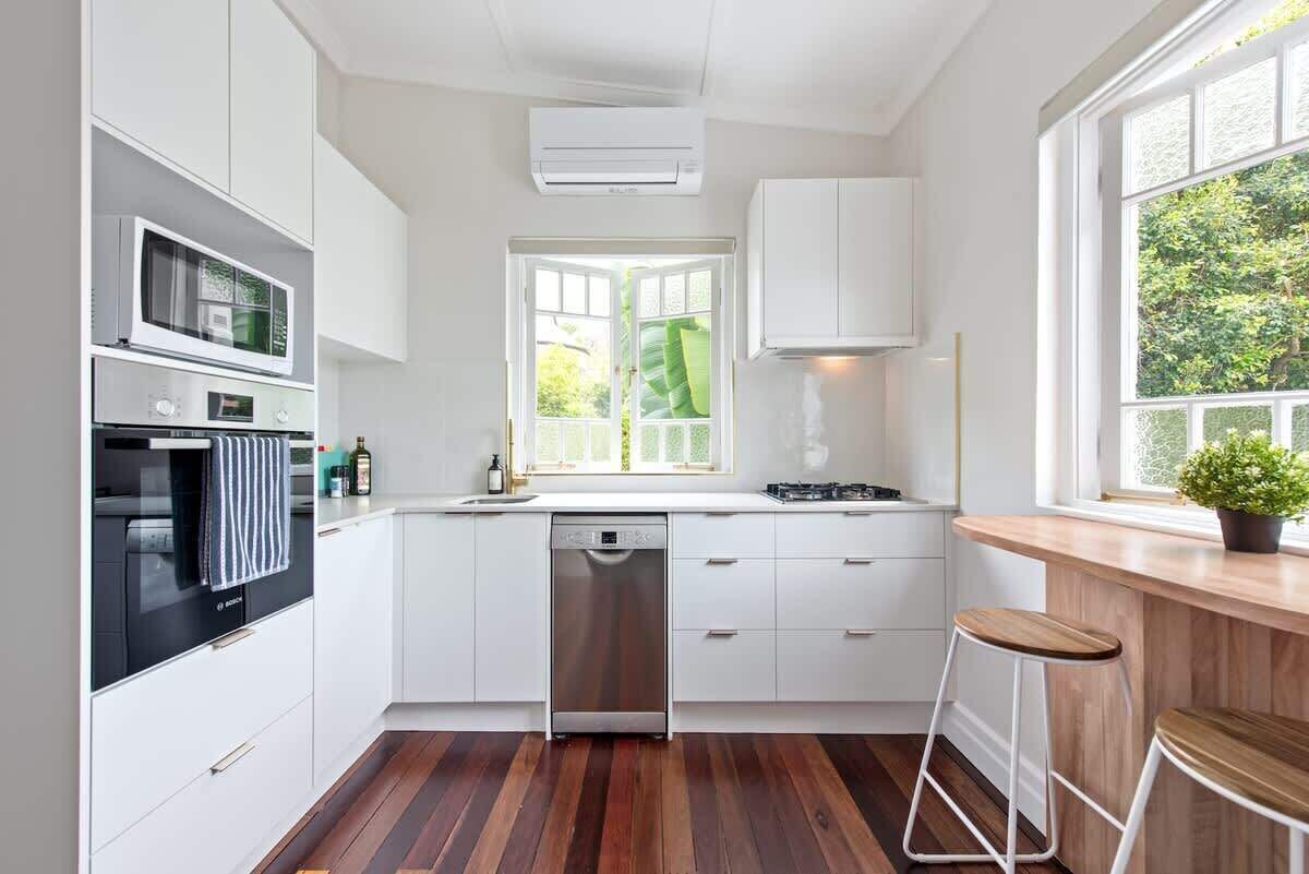 A modern kitchen with white cabinetry, a dishwasher, a microwave, and a stove.