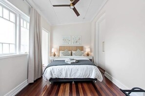 A bedroom with a bed, bedside lamps, a ceiling fan, and artwork on the wall. - Art Deco With Modern Twist! 1bed-1bath-1car-new Farm (Brisbane)