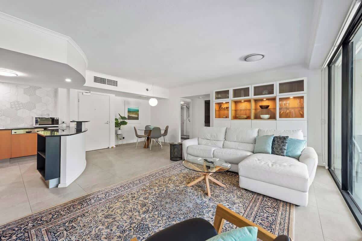 A modern living room with a sofa, coffee table, and a dining area with chairs.
