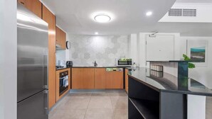 Una cucina moderna con elettrodomestici in acciaio inox, mobili in legno e pavimento piastrellato.