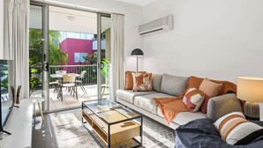 A modern living room with a sofa, coffee table, and a balcony with outdoor furniture. - Home Away From Home! 2bed/1bath/car/pool~2kms CBD (Brisbane)