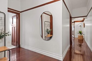 A hallway with wooden flooring, a large mirror, and a door leading to another room. - Art Deco in Ascot! ~ 2 Bed / 1 Bath / 1 Car (Brisbane)