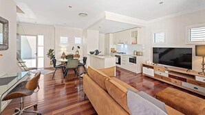 Un salon moderne avec un canapé, un téléviseur et un coin repas.
