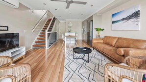 A modern living room with a sofa, TV, and a staircase. - Convenient + Spacious! 3bed/2.5bath/1car~townhouse (Brisbane)