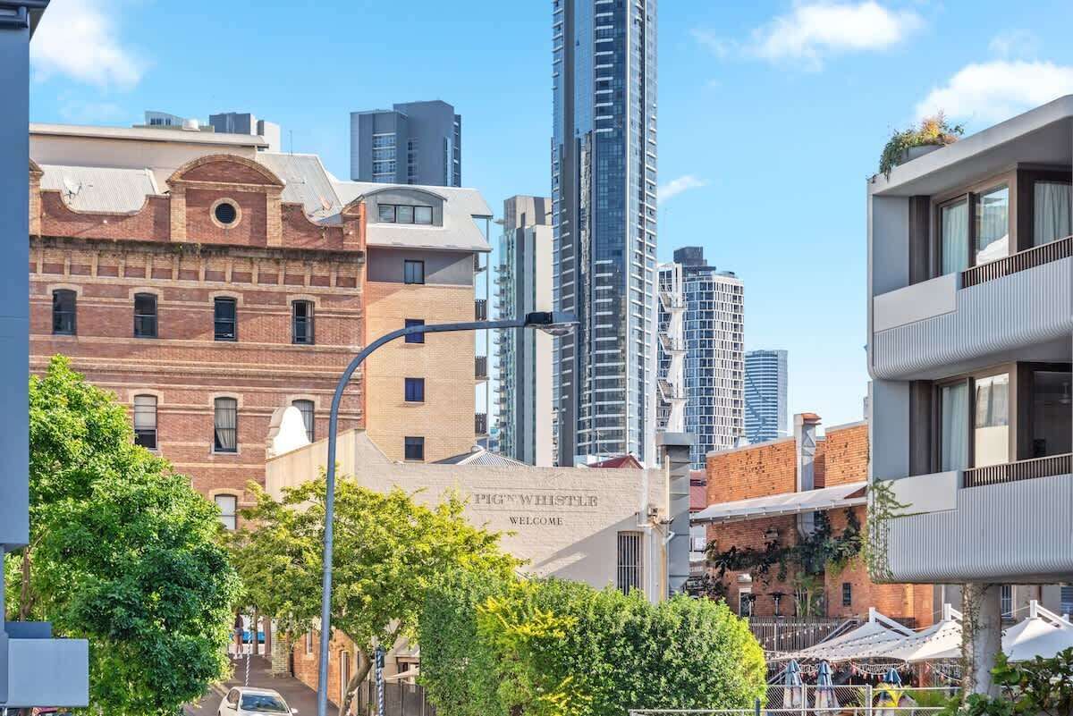 A cityscape with a mix of modern and historic buildings, including a prominent tall skyscraper and a building with a 'Welcome' sign.