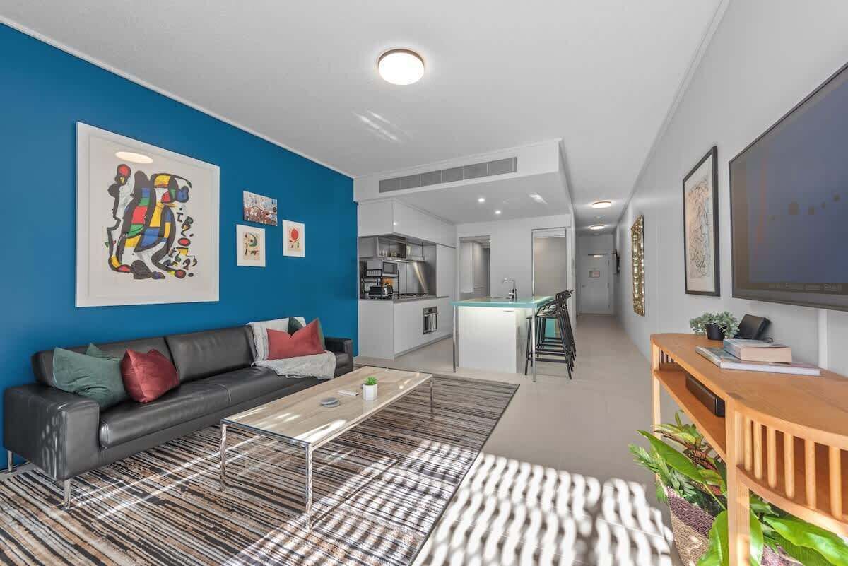 A modern living room with a sofa, coffee table, and artwork on the wall.