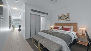 Quarto de hotel moderno com uma cama grande, um banco, uma escrivaninha e uma cadeira.