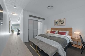 Ein modernes Hotelzimmer mit einem großen Bett, einer Bank, einem Schreibtisch und einem Stuhl.