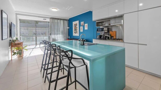 Cozinha moderna com ilha central, banquetas e vista para o exterior.