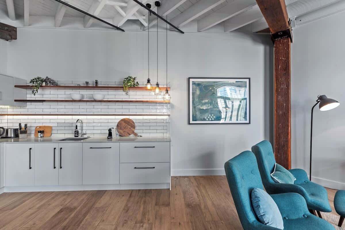 Une cuisine moderne avec des armoires blanches, un plan de travail en bois et des luminaires suspendus.