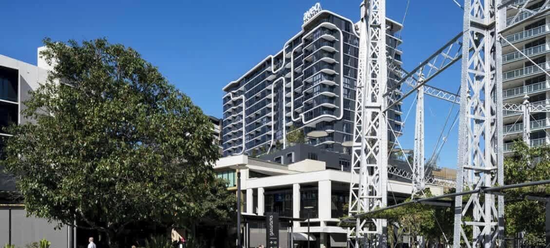 Un hotel de varios pisos con un diseño arquitectónico moderno, que cuenta con balcones y una estructura central destacada.